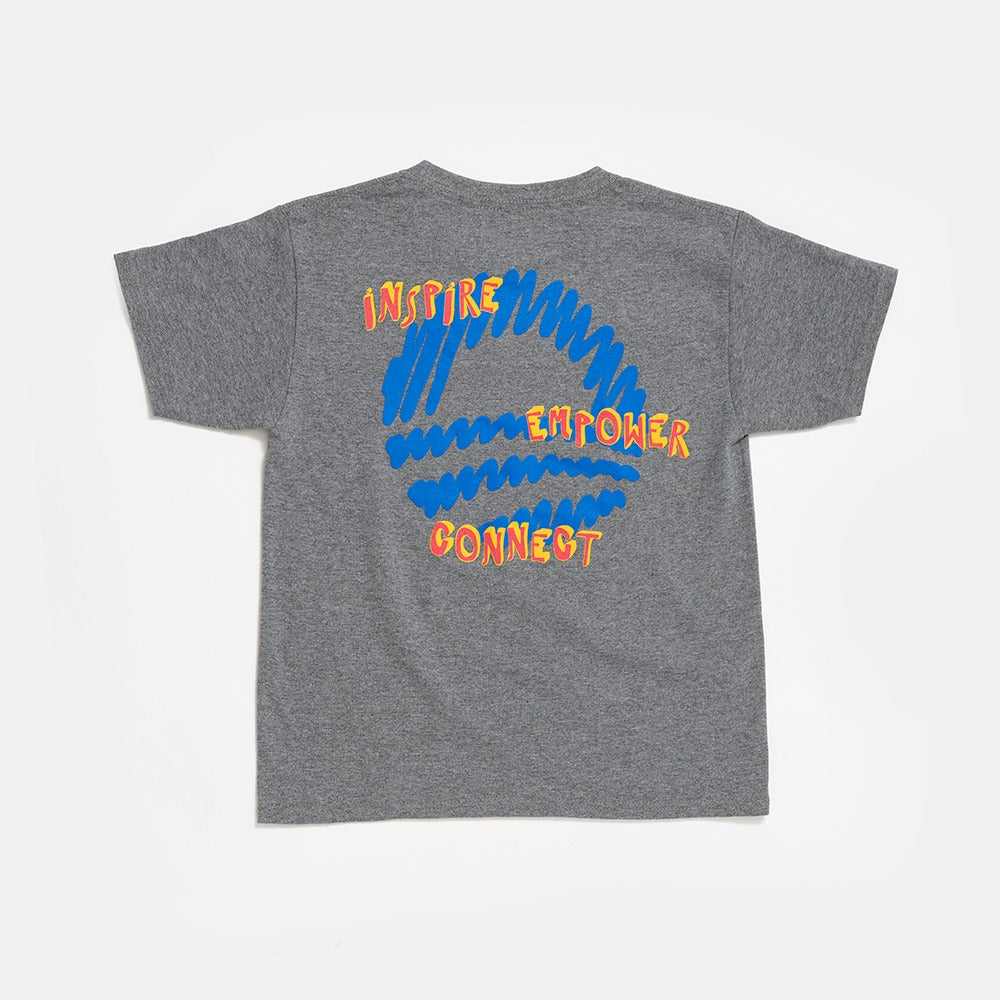 The Chicago Bring Change Home Youth T-Shirt is gray with a large blue scribble on the back and bold yellow and orange words: “INSPIRE,” “EMPOWER,” and “CONNECT.”.