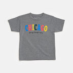The Chicago Bring Change Home Youth T-Shirt is a gray short-sleeve shirt with “CHICAGO” in colorful, bold letters and “Bring Change Home” below, inspired by the Obama Foundation.