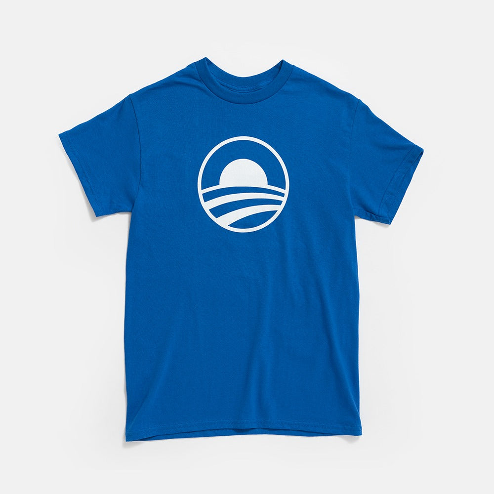 The Obama Presidential Center Symbol T-shirt features a blue design with a white rising sun graphic over stylized stripes, inspired by the Center, printed on the chest against a plain white background.