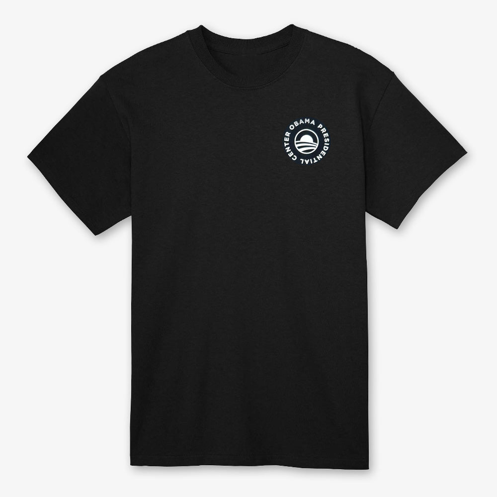 The black Obama Presidential Center Script T-Shirt features a small white circular logo on the upper left chest with “OBAMA PRESIDENTIAL CENTER” around an abstract O, inspired by Chicago’s South Side.