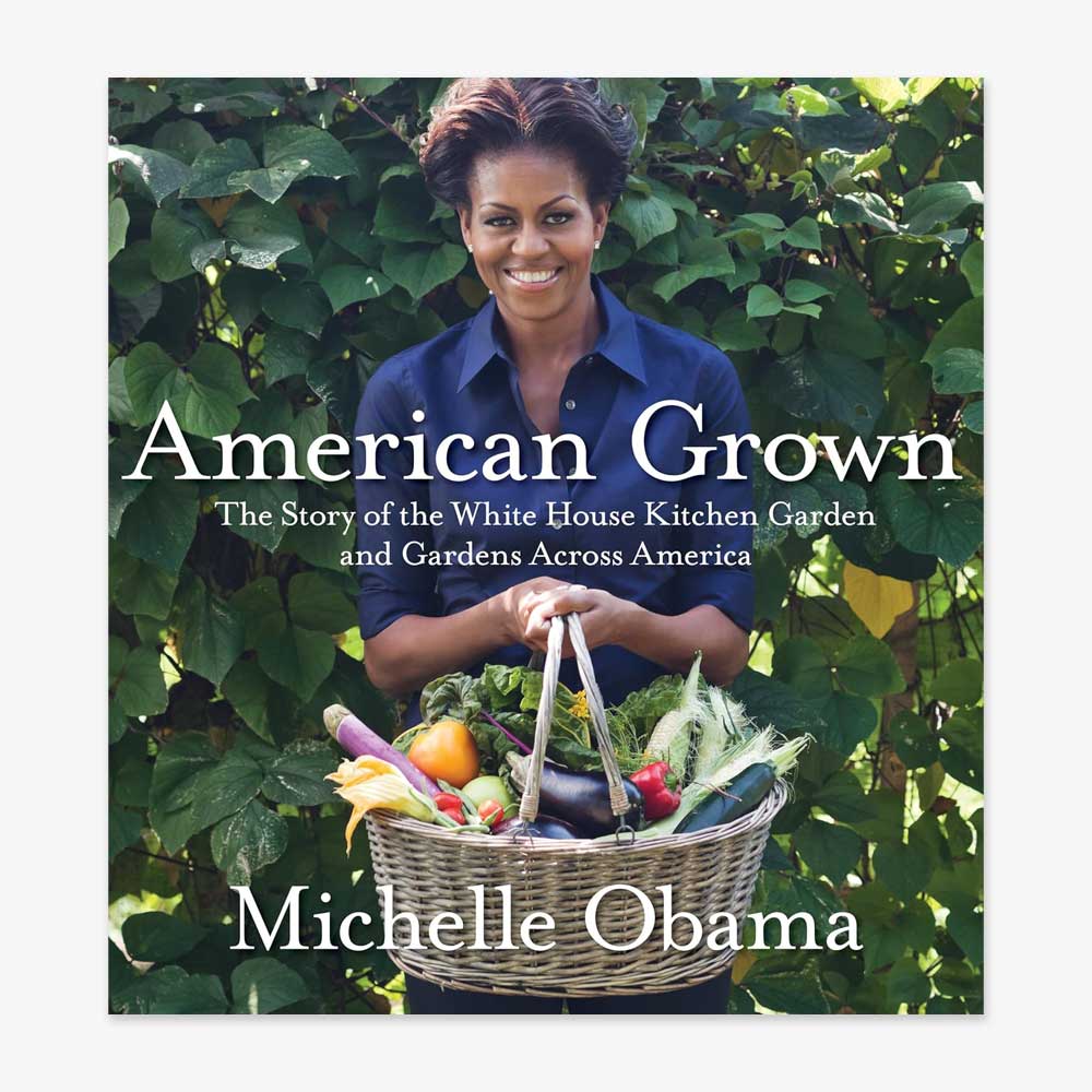 Michelle Obama stands before green foliage, smiling with a basket of vegetables. The cover displays the title: American Grown: The Story Of The White House Kitchen Garden And Gardens Across America.