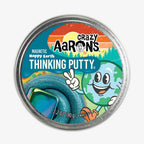 Happy Earth Putty comes in a round tin with a smiling cartoon Earth giving a peace sign on the label, set against a sunset background. Inside is teal magnetic putty—perfect as a fun STEAM sensory toy.