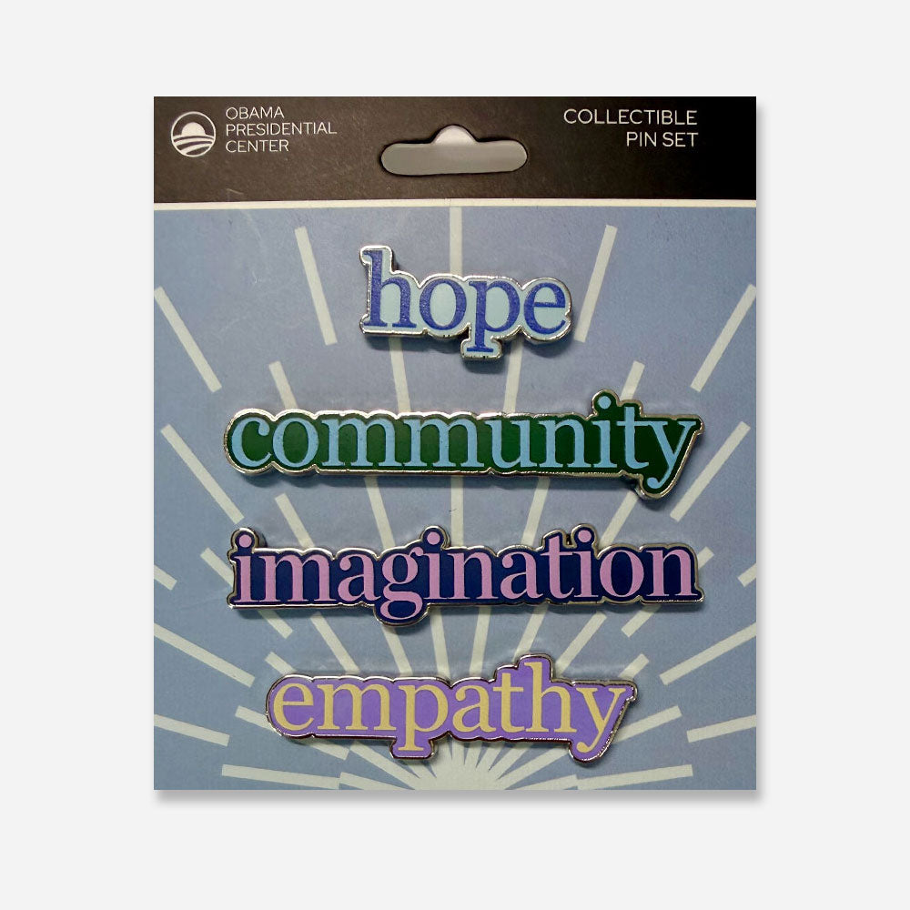 The Obama Presidential Center Pin Set features enamel pins with the words hope, community, imagination, and empathy in colorful text on a blue background with white rays, arranged vertically.