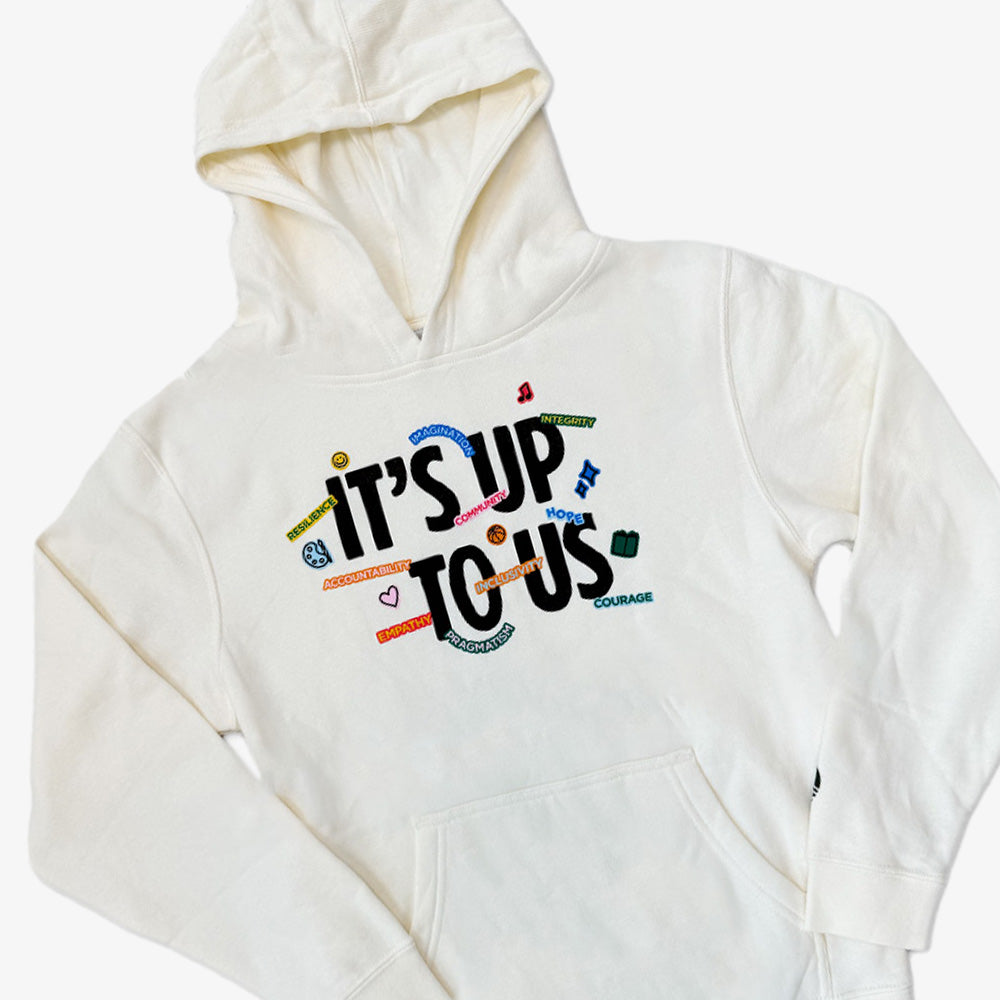 The Obama Presidential Center Stickers Youth Hooded Sweater is a white hoodie with a hood and front pocket, displaying “ITS UP TO US” in bold and colorful words like Unity, Kindness, Hope, and Courage surrounding the main text.