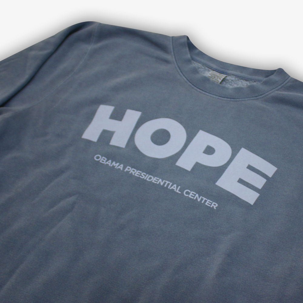 A black Obama Presidential Center Hope Sweatshirt with "HOPE" in large white letters above "OBAMA PRESIDENTIAL CENTER," inspired by vintage crewnecks and supporting the Obama Foundation.