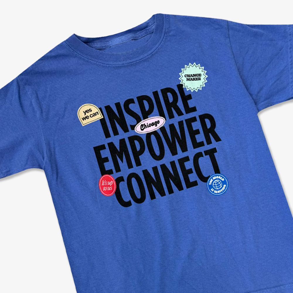 The Obama Presidential Center Stickers Youth T-Shirt is a blue tee featuring bold black "INSPIRE EMPOWER CONNECT" text and colorful badges including “yes we can,” “CHANGEMAKER,” “It’s up to us,” and a Chicago blue circle seal.