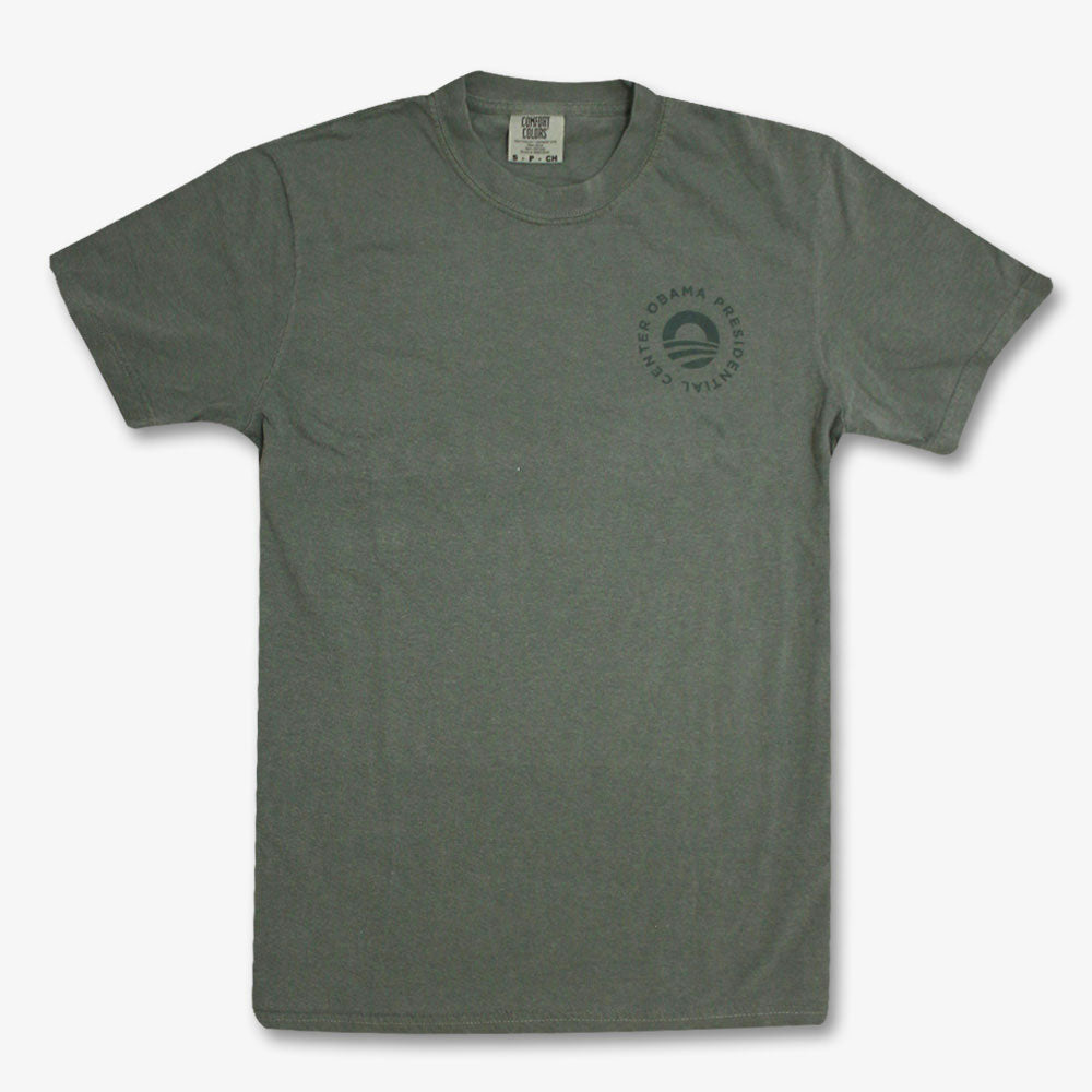 The Obama Presidential Center Hope to Action T-shirt is a gray short-sleeve tee with a small circular logo and "Obama Presidential Center" around a stylized “O” on the upper left chest, shown laid flat on a white background.
