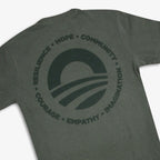 The Obama Presidential Center Hope to Action T-shirt is a gray tee with a back circular logo featuring a sunrise graphic and the words: Resilience, Hope, Community, Courage, Empathy, Imagination—inspired by the Obama Foundation.