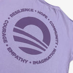 The Obama Presidential Center Hope to Action T-shirt is a lavender tee with a large circular stylized horizon graphic and bold words—RESILIENCE, HOPE, COMMUNITY, NATION, IMAGINATION, EMPATHY, COURAGE—for inspiring wear.