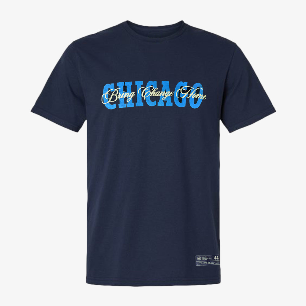 Introducing the Obama Presidential Center Chicago Script T-Shirt—a navy blue tee showcasing “CHICAGO” in bold light blue lettering, with “Bring Change Home” elegantly scripted in cursive gold and white across the front. This stylish shirt celebrates the spirit of the Obama Foundation and the forthcoming Obama Presidential Center.