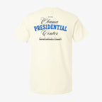 The back of the Obama Presidential Center Script T-shirt in ecru features blue and black text displaying “Obama Presidential Center” and “Inspire Empower & Connect,” includes the establishment year, city names like Chicago South Side, and a phrase about inspiration.