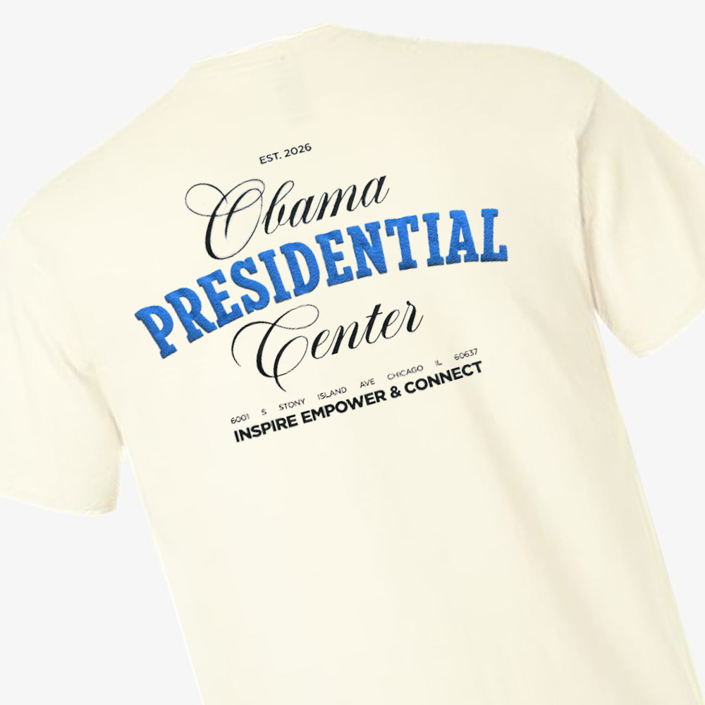 Introducing the Obama Presidential Center Script T-shirt in ecru, featuring bold black and blue text on the back—“Obama Presidential Center, EST. 2026, 601 S Stony Island Ave Chicago 60637, Inspire Empower & Connect”—celebrating the essence of the Obama Foundation’s vision on Chicago’s vibrant South Side.