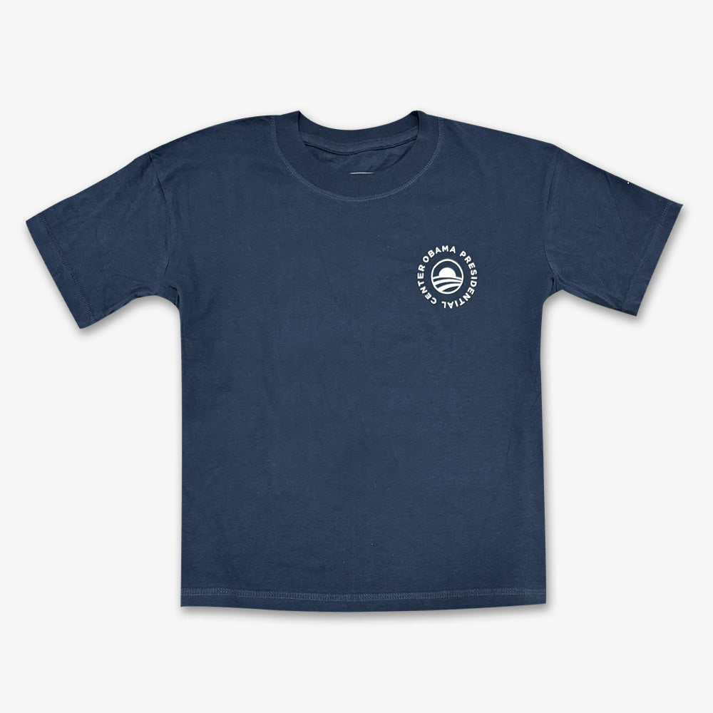 Denim Obama Presidential Center Home Court T-shirt with a small circular logo and stylized "O" on the left chest, displayed flat on a white background.