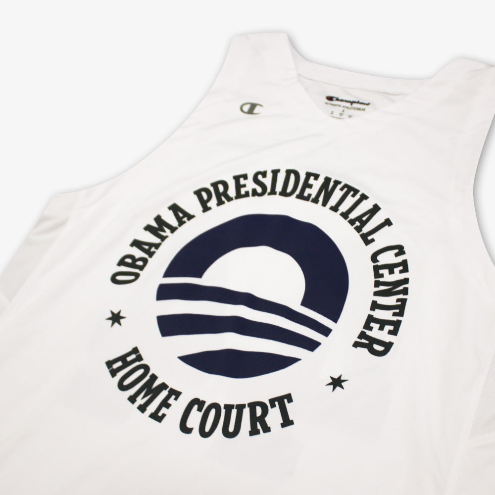 The Obama Presidential Center Home Court Jersey is a white basketball jersey by Champion, featuring “Obama Presidential Center Home Court” in black around a sun-and-waves logo.