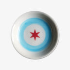 The Chicago Star Trinket Dish is a round white handmade porcelain plate featuring a red six-pointed star in the center and two light blue concentric circles, crafted by a Black-owned business.