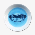 The Hot Dog Trinket Dish is a small handmade porcelain plate with a blue center, featuring an illustration of a Chicago hot dog complete with relish, mustard, and peppers—perfect for showing your love of Chicago style.