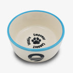 The Obama Presidential Center Pet Bowl is a ceramic pet bowl with a blue rim, handmade by a Black-owned studio. It features a black paw print and the words Inspire, Empower, and Connect inside, plus a white exterior with black logo.