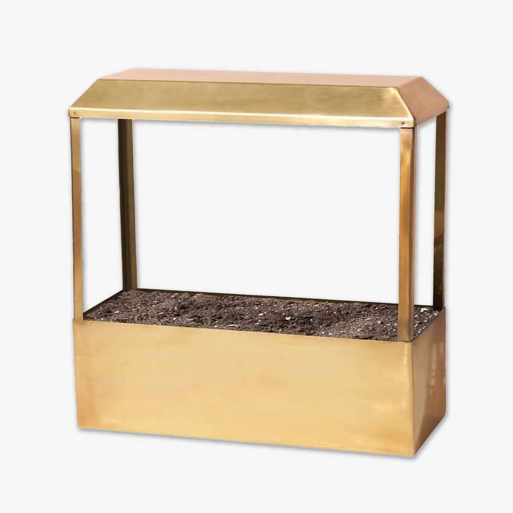 The Metal Growhouse is a gold-colored rectangular planter box with an attached canopy, perfect for indoor gardening. It’s filled with soil and displayed against a white background.