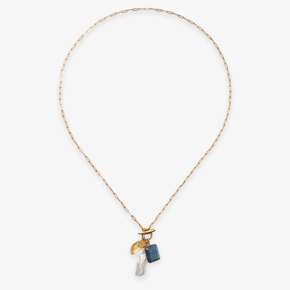 The Gemstone Mix Charm Necklace features a gold paperclip chain with three charms—a gold disk, blue rectangular gemstone, and white pearl—offering modern, sustainable artisan style ideal for everyday wear.