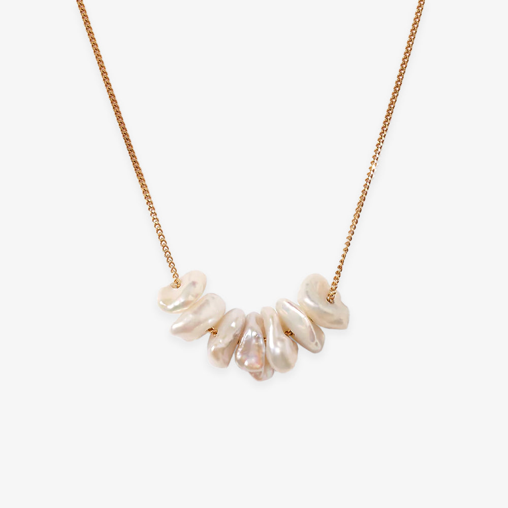 The Gold Pearl Chip Necklace features a gold plated sterling silver chain with several irregularly shaped white keshi pearls strung at the center, inspired by Chan Luu’s signature style.