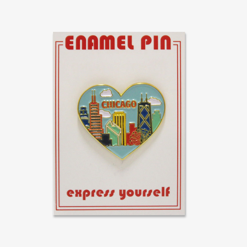 Skyline Heart Pin with vibrant Chicago buildings and clouds, displayed on a card labeled “ENAMEL PIN” and “express yourself” in red—a perfect keepsake for fans of the Obama Foundation and Chicago.