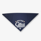 The Voted Cutest Kerchief is a navy dog bandana with "Voted Cutest" in white text, two stars, and a circular logo—an adorable accessory to enhance your pup's style.