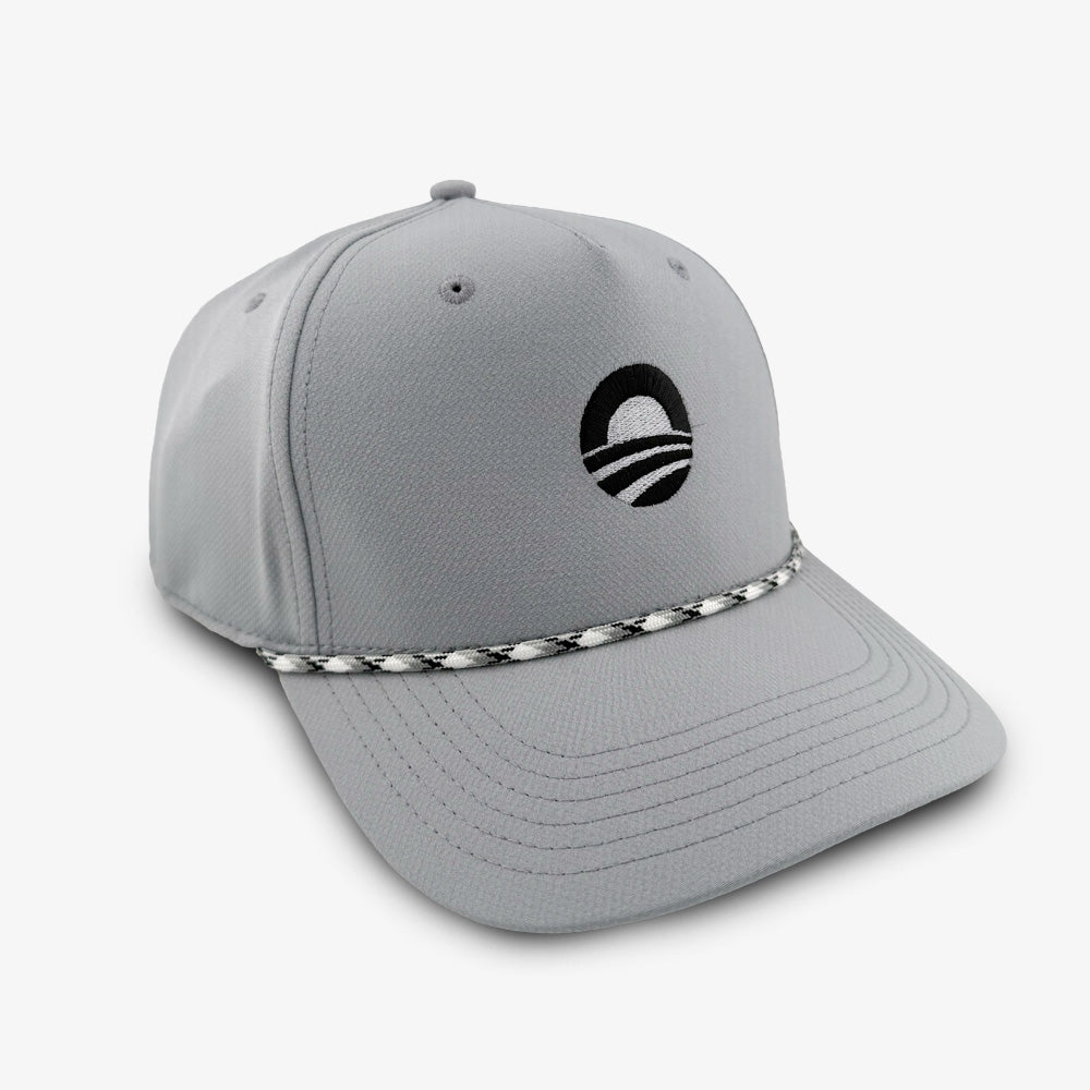 The Obama Presidential Center Golf Cap - Grey features a black circular logo on the front and a distinctive black-and-white braided rope along the base of the crown. Inspired by the Obama Presidential Center cap collection, this light gray performance cap stands out against a plain white background.