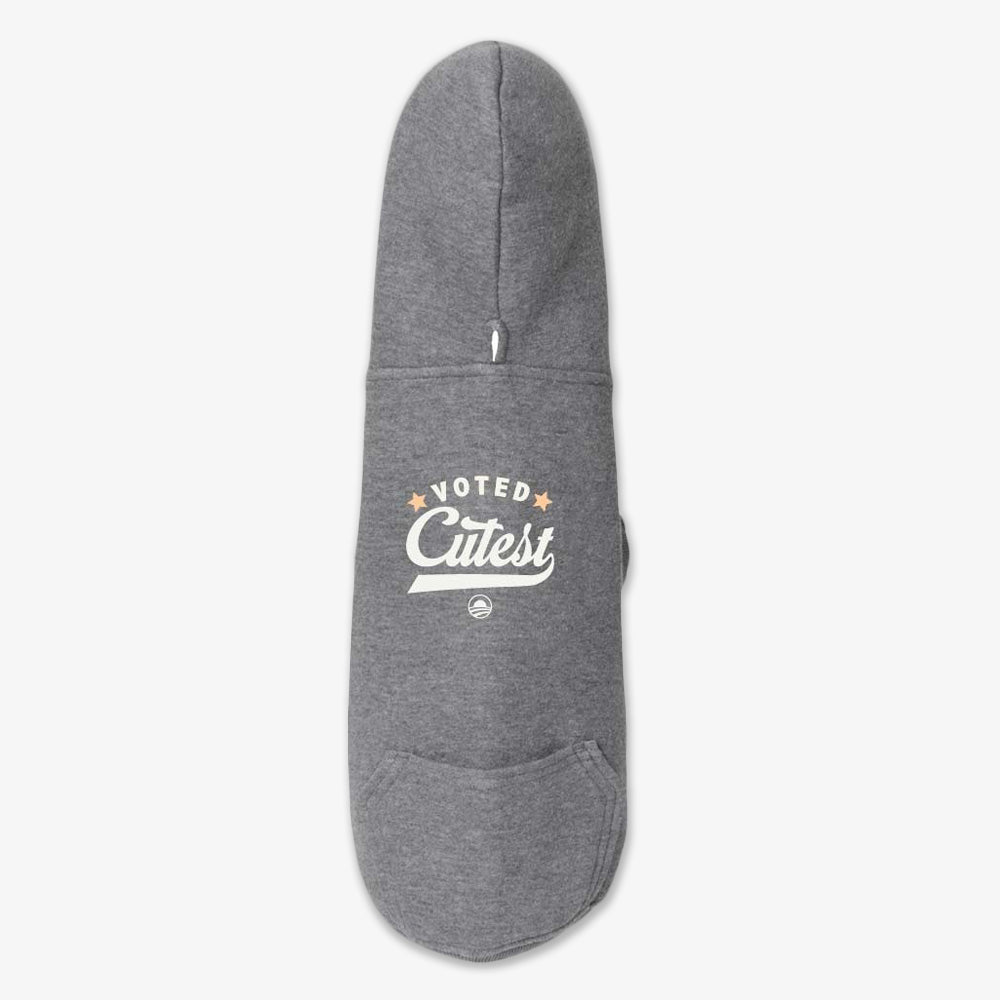The Voted Cutest Dog Hooded Sweater is a gray hoodie featuring a hood, front pocket, and "Voted Cutest" in white and gold with star accents—ideal for walks near the Obama Presidential Center.