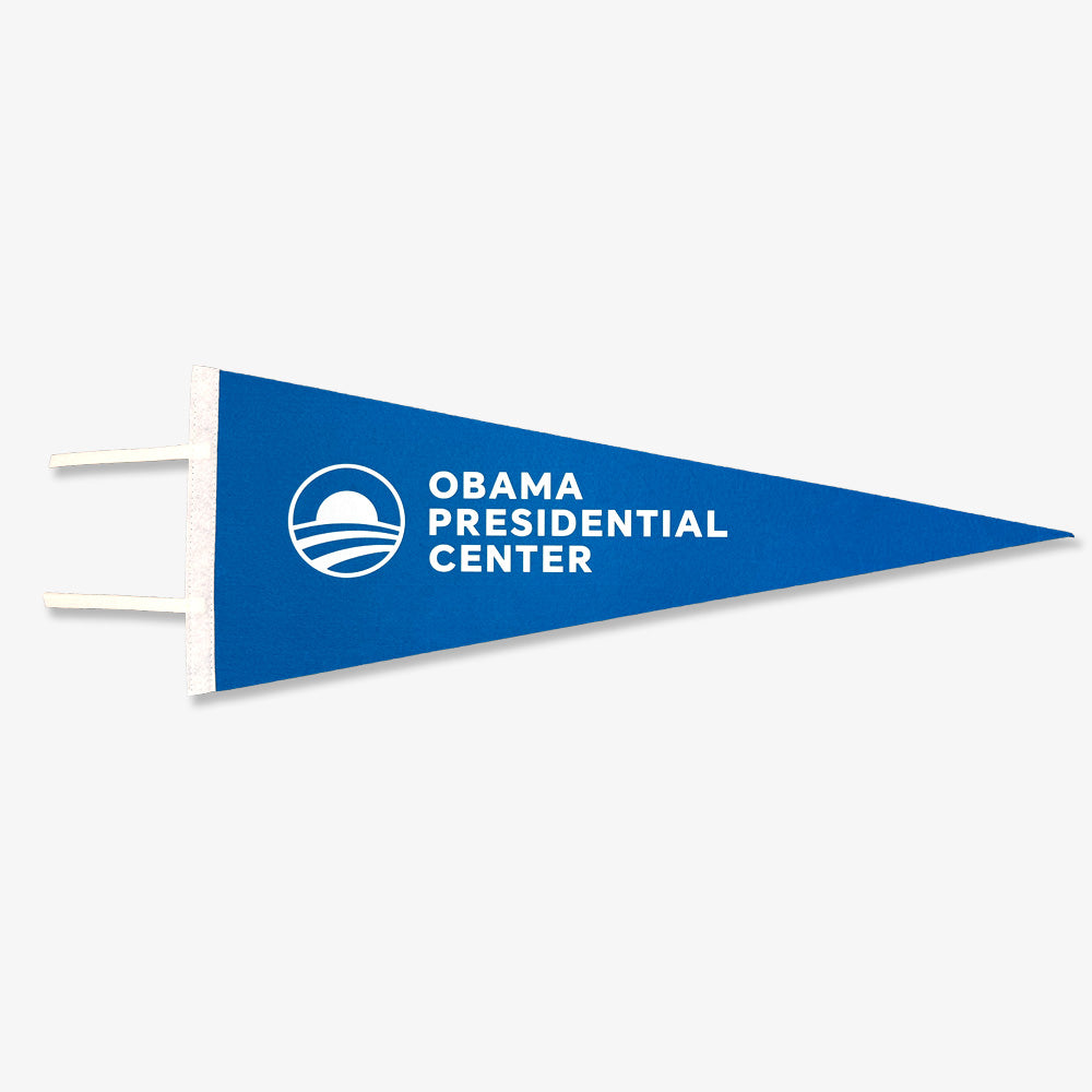 The Obama Presidential Center Home Court Pennant is blue and triangular with “Obama Presidential Center” in white text beside a rising sun logo. It includes two white ties on the left, making it a unique piece of sports memorabilia.