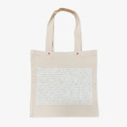 The Obama Presidential Center "You Are America" Speech Tote is a beige canvas bag with two handles and a block of dense white uppercase text covering most of the front.