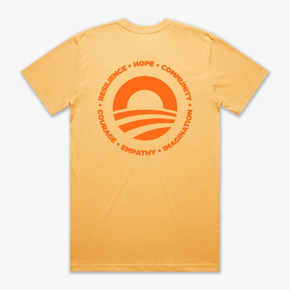 The Obama Presidential Center Hope to Action T-shirt - Sunset features a yellow design with a circular orange sun-over-waves graphic and inspiring words: RESILIENCE • HOPE • COMMUNITY • COURAGE • EMPATHY • IMAGINATION.