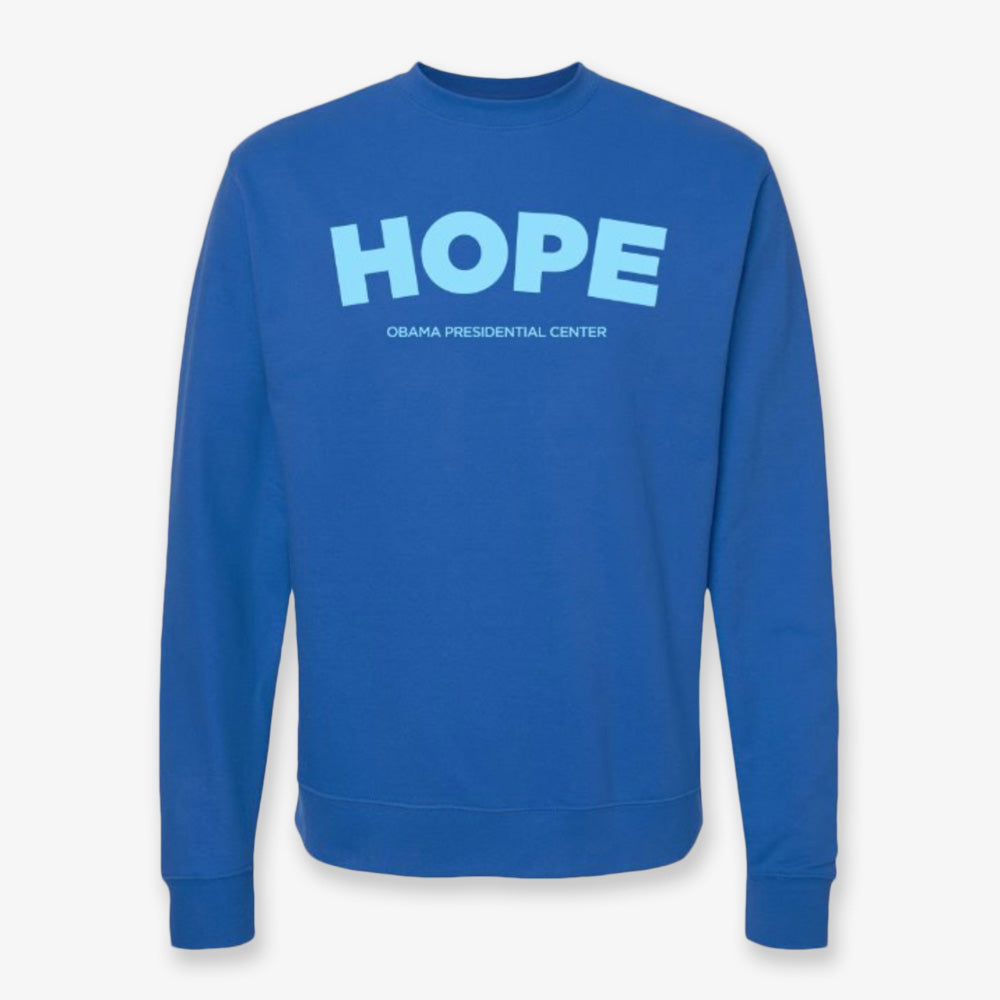 The Obama Presidential Center Hope Sweatshirt in royal blue features bold light blue “HOPE” lettering and “Obama Presidential Center” below, crafted in a classic crewneck style.
