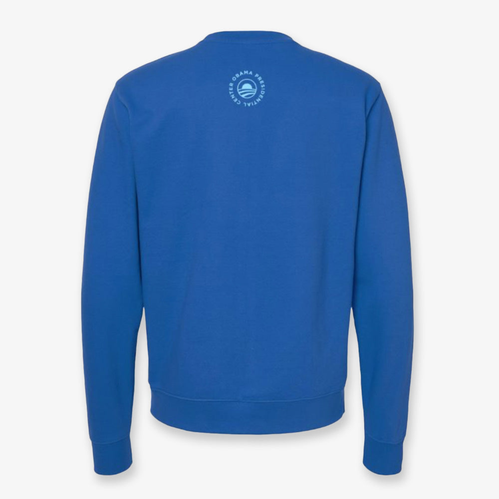 The Obama Presidential Center Hope Sweatshirt in royal blue is shown from the back, displaying a small circular white Obama Foundation logo with text and graphic near the neckline.