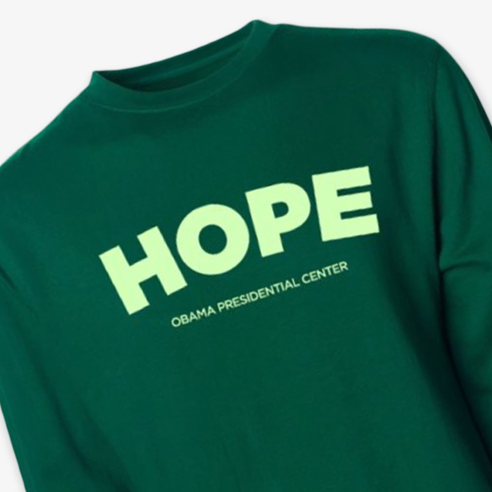 The Obama Presidential Center Hope Sweatshirt in green features "HOPE" in large, bold, light yellow letters with "Obama Presidential Center" printed underneath in smaller text.