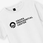 Show your support for the Obama Foundation with the Obama Presidential Center Logo Youth T-Shirt in white, featuring "Obama Presidential Center" and a circular logo with a stylized sun above curved lines printed in black.