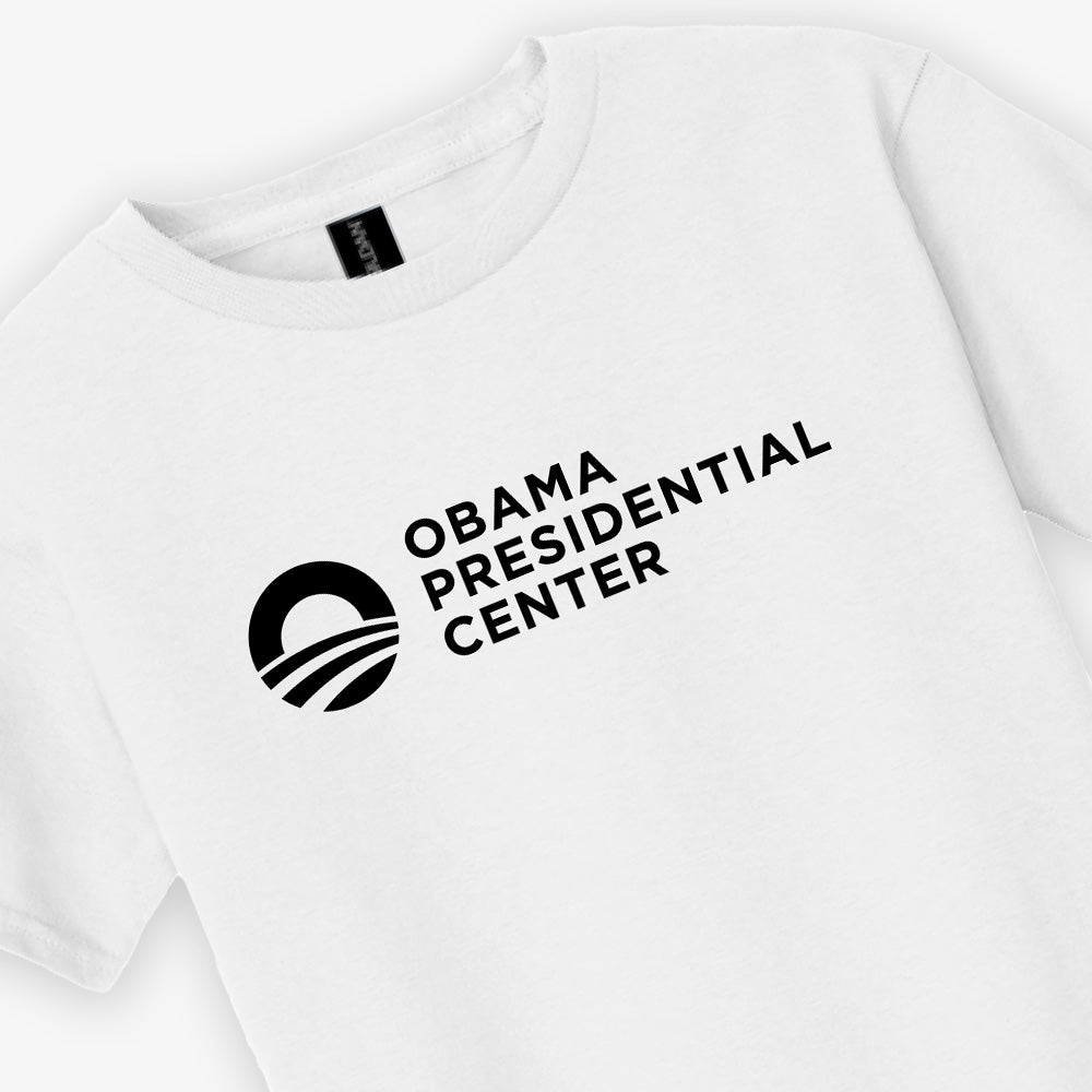 Show your support for the Obama Foundation with the Obama Presidential Center Logo Youth T-Shirt in white, featuring "Obama Presidential Center" and a circular logo with a stylized sun above curved lines printed in black.