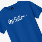 Royal blue youth unisex t-shirt, officially inspired by the Obama Foundation, featuring the Obama Presidential Center and a white circular logo printed on the front. Product name: Obama Presidential Center Logo Youth T-Shirt - Royal.