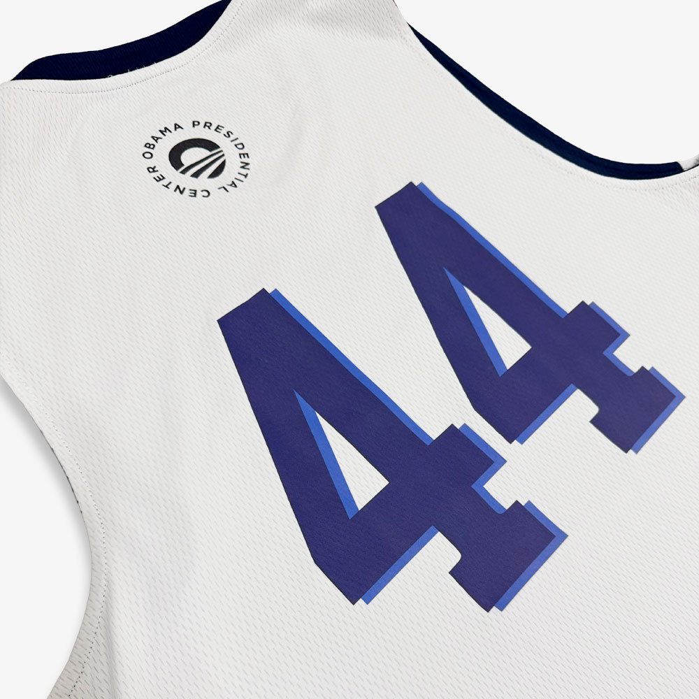 A close-up of the Obama Presidential Center Home Court Jersey - White, featuring a blue number 44 on the back and the Obama Foundation logo near the collar.