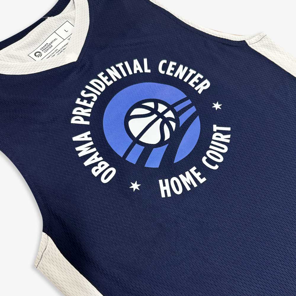 The Obama Presidential Center Home Court Youth Jersey - Navy features white and blue details with “Obama Presidential Center Home Court” text around a stylized basketball and hoop logo.