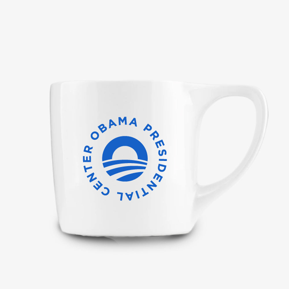 The Obama Presidential Center Logo Mug is a white ceramic mug with a blue circular logo of a rising sun and "OBAMA PRESIDENTIAL CENTER" text—an ideal official center mug.