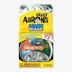 A package of Liquid Glass Putty in yellow and clear packaging displays the crystal-clear putty inside a metal tin, emphasizing its unique STEAM appeal with product information and a warning label featured.