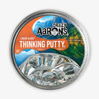 A 3.2 oz round tin of Liquid Glass Putty with crystal-clear putty inside, featuring a mountain lake label design, promotes STEAM learning, and is suitable for ages 3 and up.