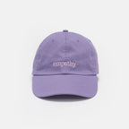 The Obama Presidential Center Empathy Cap is a lavender baseball cap with "empathy" embroidered in white lowercase letters on the front, shown against a plain white background.