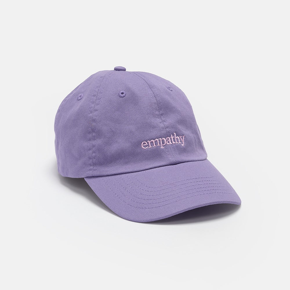 The Obama Presidential Center Empathy Cap is a lavender-purple hat with "empathy" embroidered in pink lowercase letters on the front, shown on a white background—an inspiring tribute to empathy.