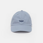 The Obama Presidential Center Hope Cap - Blue features "hope" embroidered in dark blue lowercase letters on a light blue cap, reminiscent of the iconic Obama hat, displayed against a plain white background.