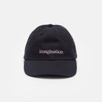 The Obama Presidential Center Imagination Cap is a black baseball cap with "imagination" embroidered in white lowercase letters on the front, shown on a plain light gray background—an ideal unique piece of Obama Foundation merchandise.