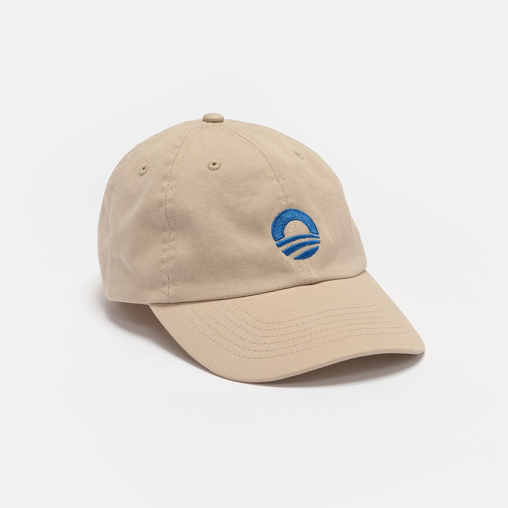 The Obama Presidential Center Symbol Cap is an off-white hat with the official Obama Foundation logo embroidered in blue on the front, shown against a plain white background.