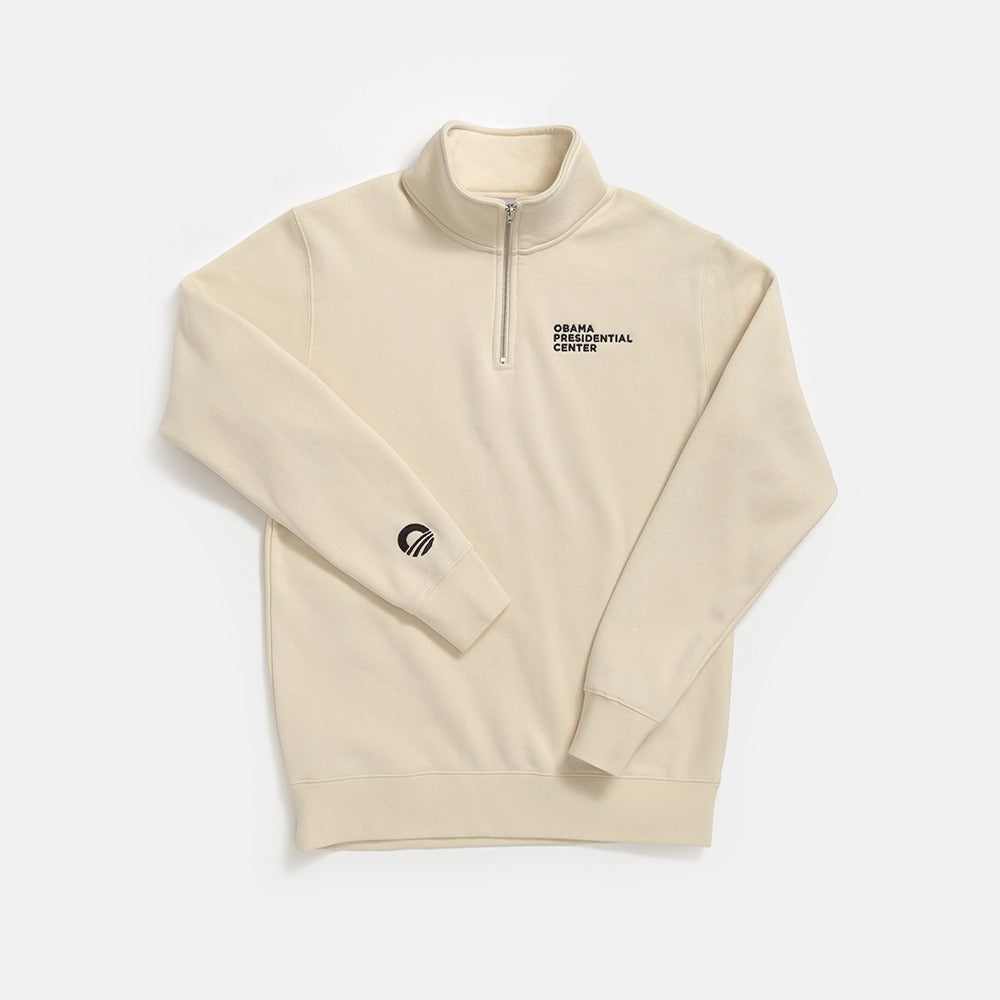 The Obama Presidential Center Quarter Zip Sweatshirt is a beige pullover with center text on the left chest and a small black circular logo on the right sleeve, shown laid flat on a white background.