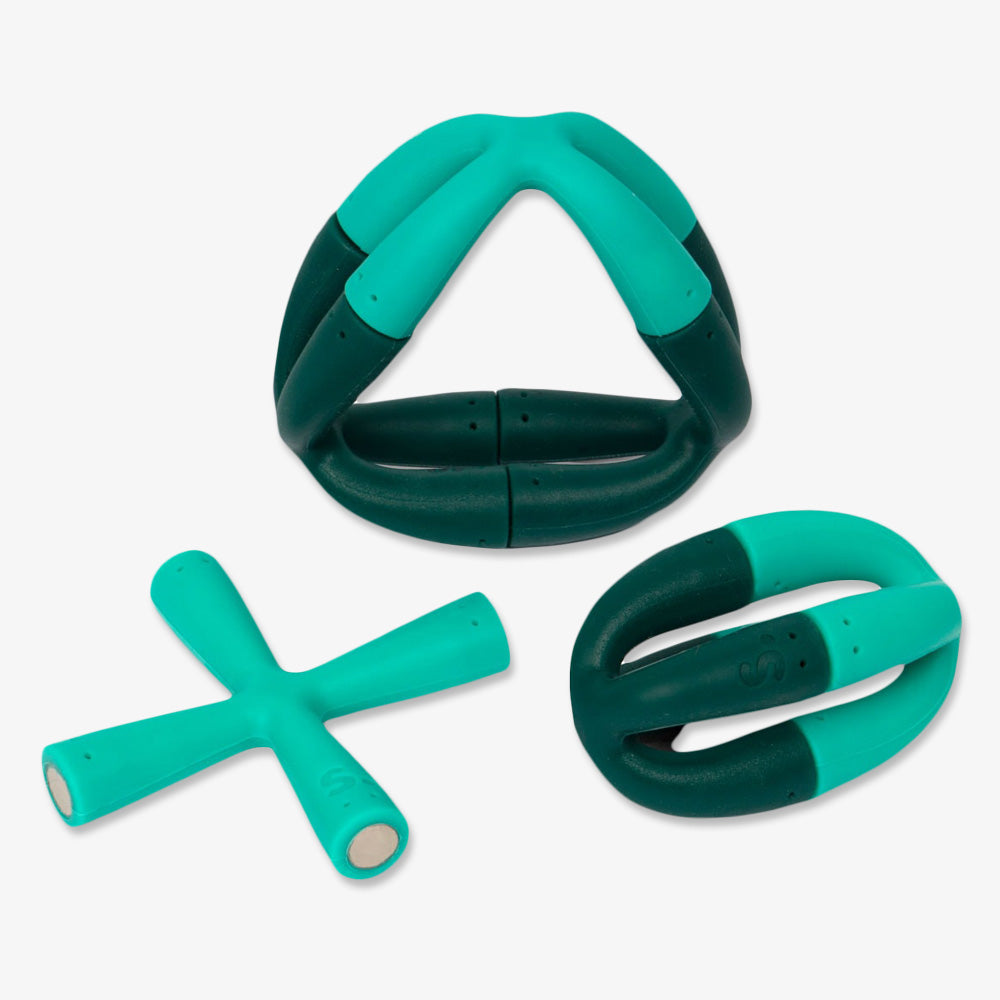 The Evergreen Flex Set includes three teal and dark green rubber dog toys—triangle, oval, and X shapes with smooth edges—ideal for stress relief or as a creative addition to any educational set.