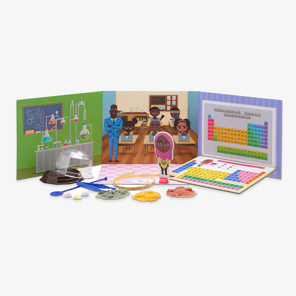 The Chemistry STEAM Kit includes lab tools, colored powders, tablets, a periodic table puzzle, and a classroom backdrop with illustrated students, teacher, and science equipment—perfect for fun DIY crystal making activities.
